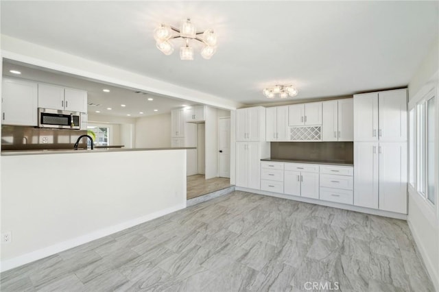 kitchen with backsplash, kitchen peninsula, white cabinetry, and sink