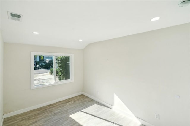 empty room featuring vaulted ceiling and light hardwood / wood-style flooring