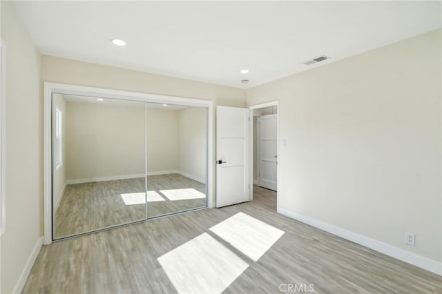 unfurnished bedroom with light hardwood / wood-style floors and a closet