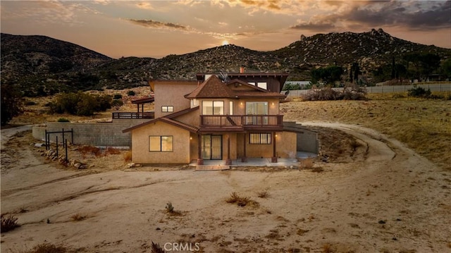 back house at dusk with a mountain view and a balcony