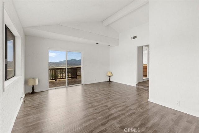 empty room with hardwood / wood-style floors and lofted ceiling with beams