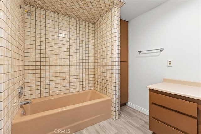 bathroom with hardwood / wood-style floors, vanity, and tiled shower / bath