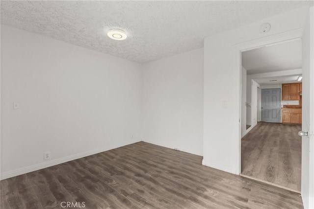 spare room featuring dark hardwood / wood-style flooring and a textured ceiling