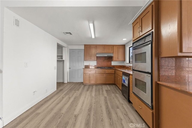 kitchen featuring decorative backsplash, sink, stainless steel appliances, and light hardwood / wood-style flooring