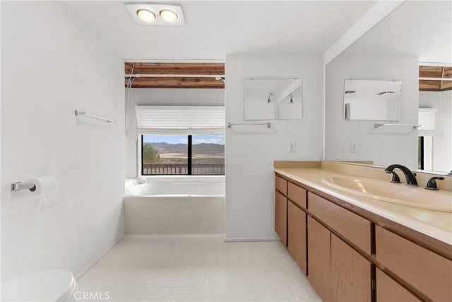 bathroom with vanity, toilet, and tiled tub