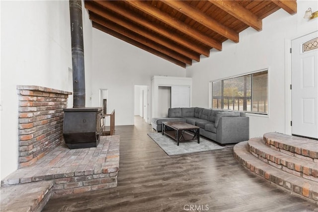 living room featuring beamed ceiling, a wood stove, dark wood-type flooring, and high vaulted ceiling