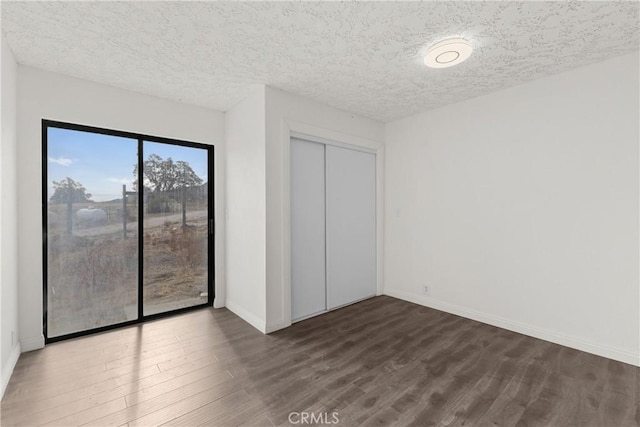 unfurnished bedroom featuring dark hardwood / wood-style flooring, a textured ceiling, and a closet