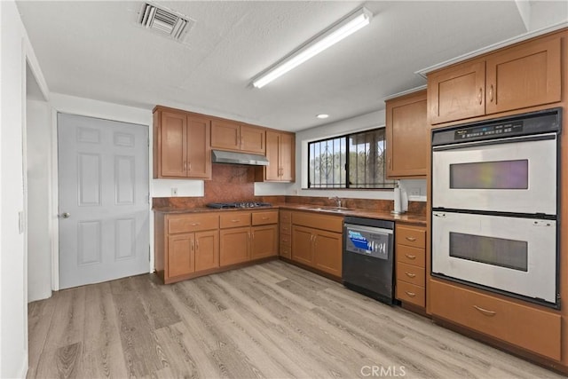 kitchen with sink, light hardwood / wood-style flooring, decorative backsplash, black dishwasher, and double oven