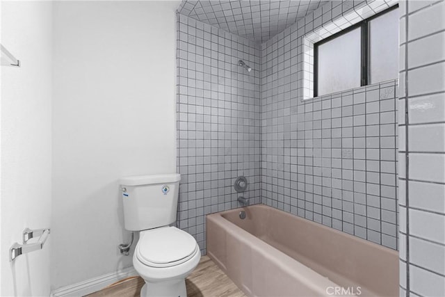 bathroom with hardwood / wood-style flooring, toilet, and tiled shower / bath