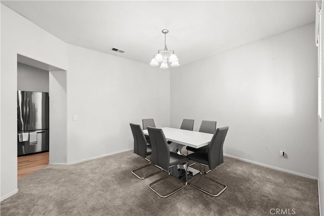 dining space featuring baseboards, carpet floors, visible vents, and an inviting chandelier