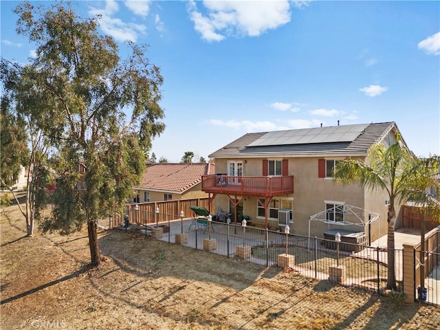 rear view of house with a patio, a fenced backyard, roof mounted solar panels, and stucco siding