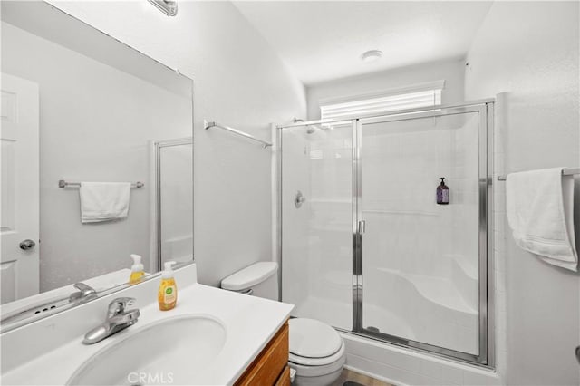 bathroom featuring vanity, toilet, and a shower with shower door