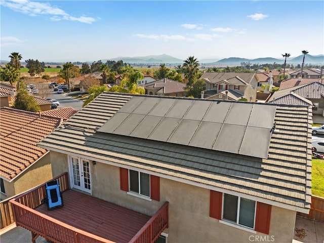 exterior space with a mountain view, french doors, and solar panels