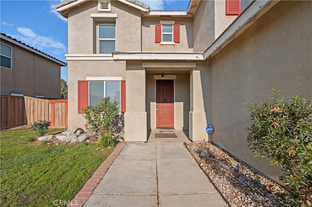 doorway to property featuring a tiled roof, fence, and stucco siding