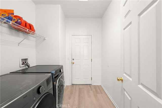 laundry area with light hardwood / wood-style flooring and washer and dryer