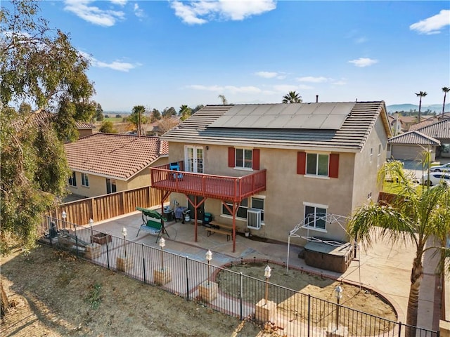 rear view of property with a hot tub, solar panels, a patio, a fenced backyard, and stucco siding