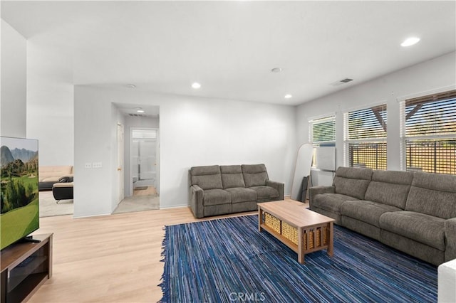 living room with recessed lighting, visible vents, and wood finished floors