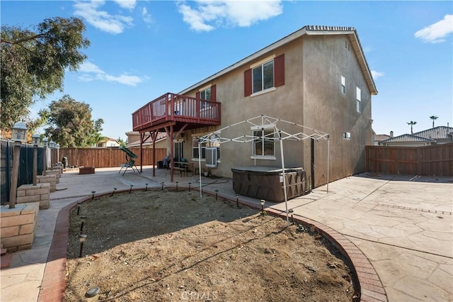 back of house featuring a patio, cooling unit, a fenced backyard, stucco siding, and a hot tub