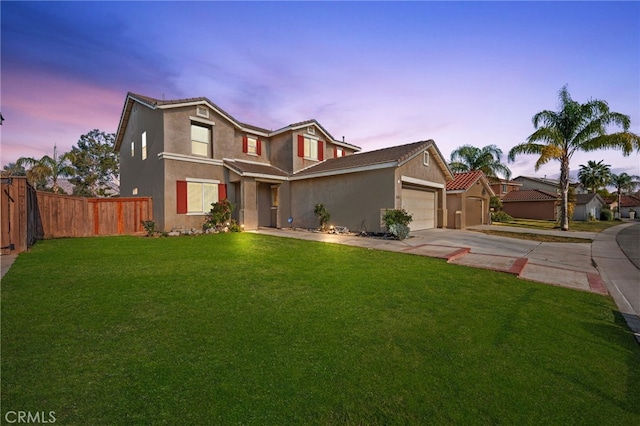 traditional home with a garage, fence, concrete driveway, stucco siding, and a front yard