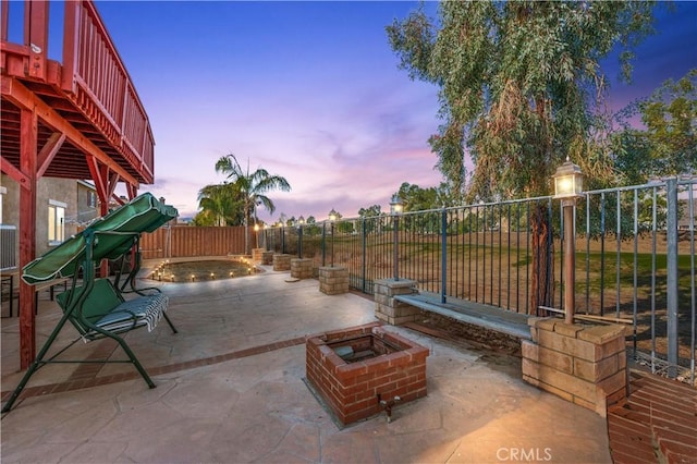 patio terrace at dusk featuring a fire pit and a fenced backyard