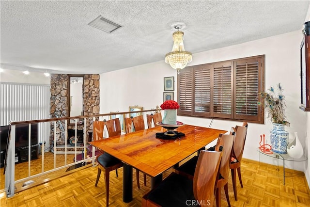 dining space with light parquet floors, a textured ceiling, and an inviting chandelier