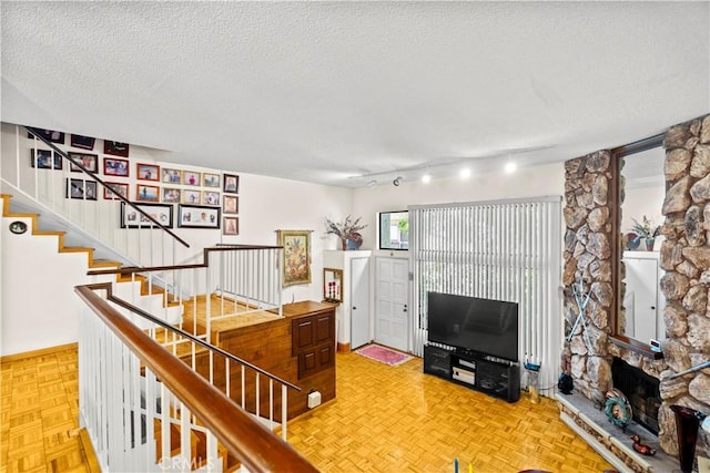 living room with a fireplace, parquet floors, and a textured ceiling