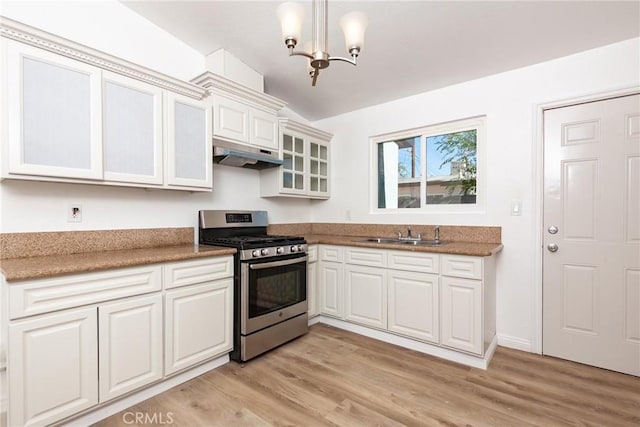 kitchen with white cabinetry, sink, stainless steel gas range oven, a notable chandelier, and pendant lighting