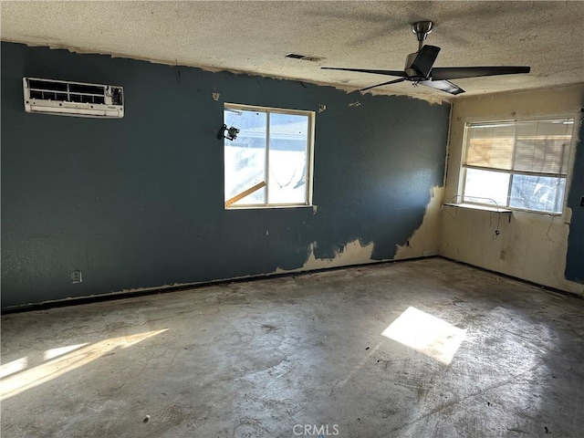 unfurnished room with a textured ceiling, a wall unit AC, and ceiling fan