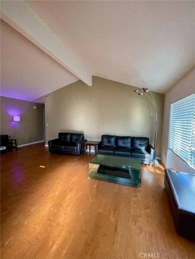 living room with hardwood / wood-style flooring and vaulted ceiling with beams