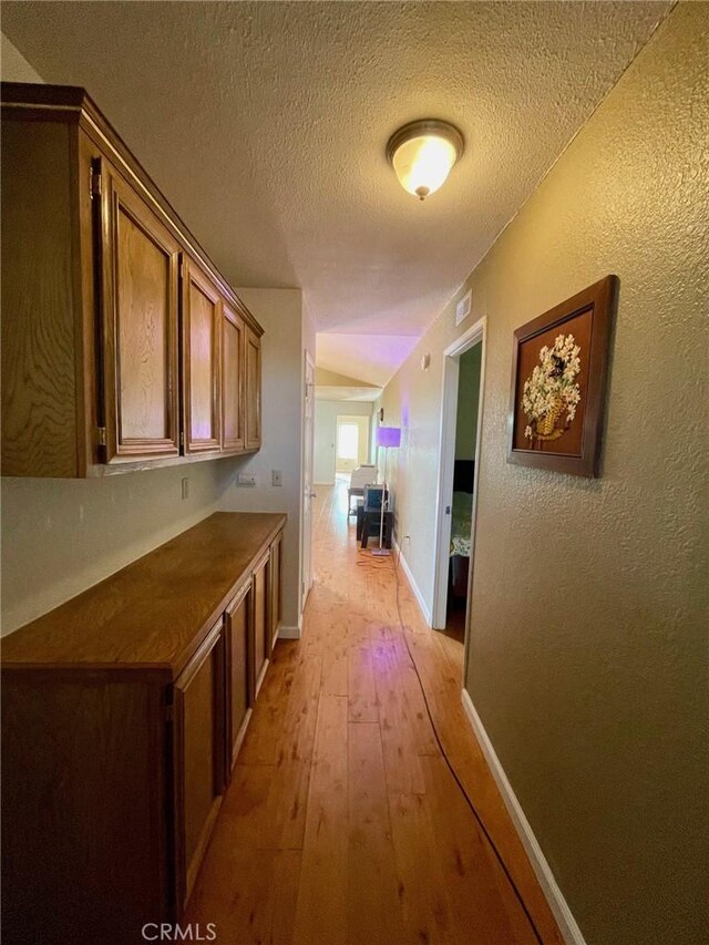 hallway with light hardwood / wood-style flooring and a textured ceiling