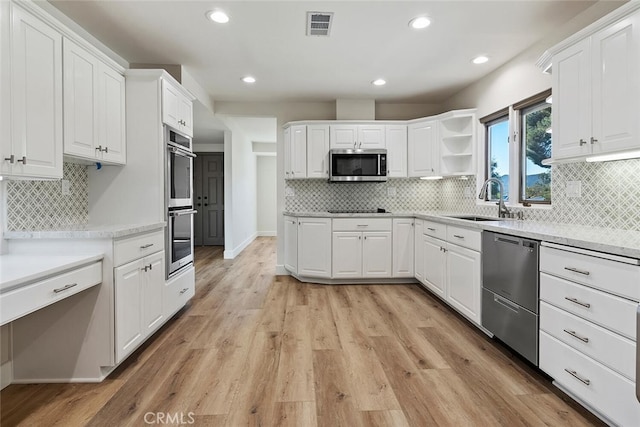 kitchen with sink, white cabinets, stainless steel appliances, and light hardwood / wood-style floors