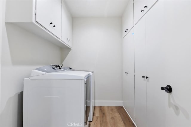 laundry area with cabinets, light wood-type flooring, and washing machine and clothes dryer