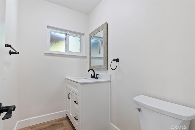 bathroom with hardwood / wood-style flooring, vanity, and toilet