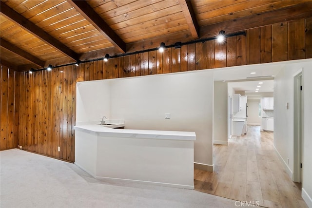 interior space with beamed ceiling, wood walls, wooden ceiling, and light hardwood / wood-style flooring