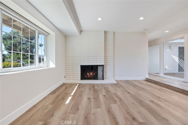 unfurnished living room with light hardwood / wood-style flooring and a brick fireplace