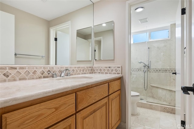 bathroom with tasteful backsplash, vanity, a shower with shower door, and toilet