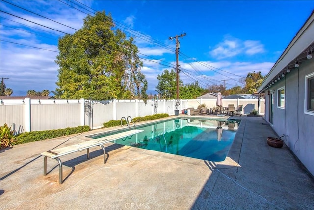 view of swimming pool featuring a diving board and a patio