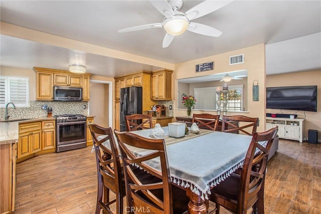 dining room featuring ceiling fan, sink, and light hardwood / wood-style floors