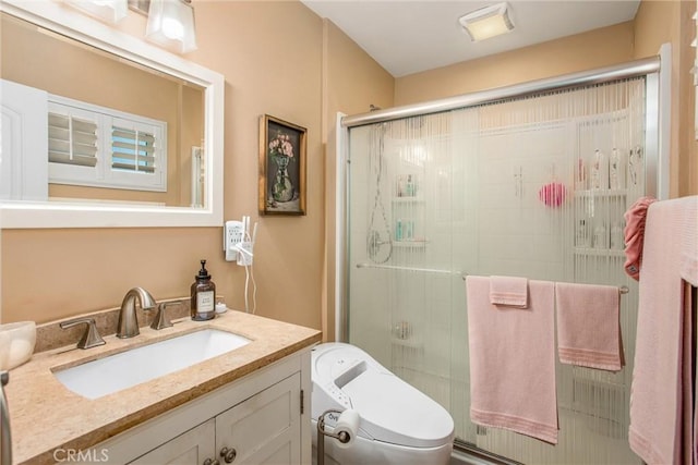 bathroom with toilet, vanity, and a shower with door