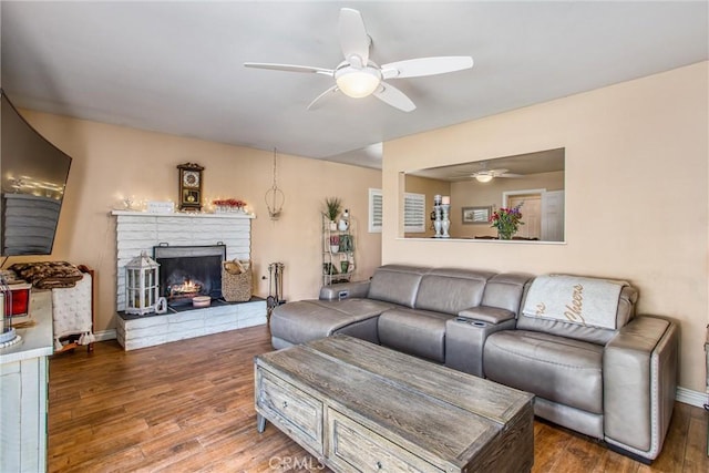 living room with ceiling fan, wood-type flooring, and a fireplace