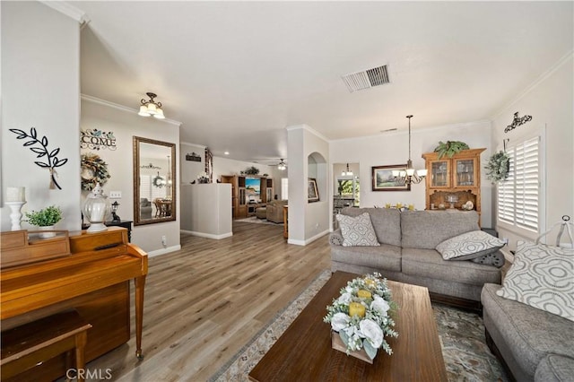 living room with wood-type flooring, ceiling fan with notable chandelier, and ornamental molding