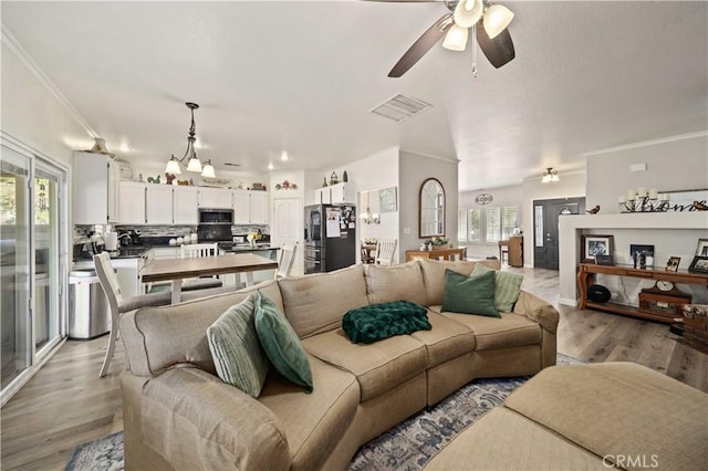 living room with ceiling fan with notable chandelier, light hardwood / wood-style floors, and crown molding