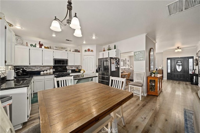 dining space with sink, ornamental molding, a chandelier, and hardwood / wood-style flooring