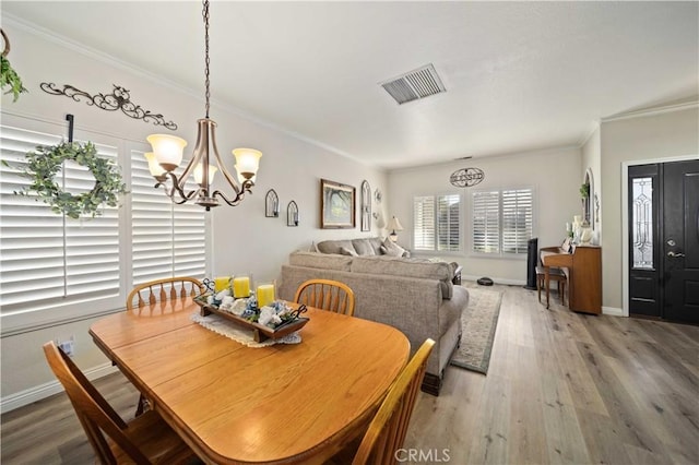 dining room featuring a chandelier, hardwood / wood-style floors, and crown molding