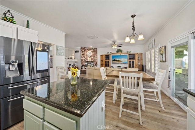 kitchen featuring stainless steel refrigerator with ice dispenser, a large fireplace, light hardwood / wood-style flooring, a kitchen island, and green cabinets