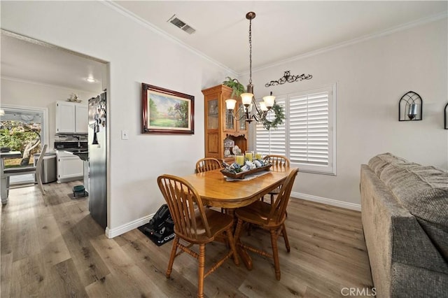 dining space featuring light hardwood / wood-style flooring, a chandelier, and ornamental molding