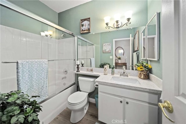 full bathroom with hardwood / wood-style flooring, vanity, enclosed tub / shower combo, and toilet