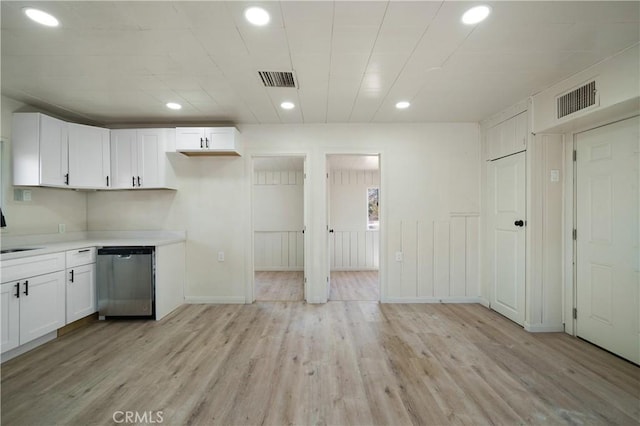 kitchen with white cabinets, light hardwood / wood-style floors, stainless steel dishwasher, and sink