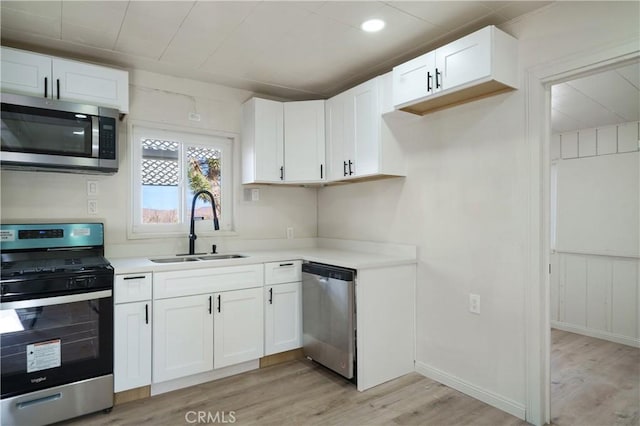 kitchen with sink, white cabinets, light hardwood / wood-style flooring, and appliances with stainless steel finishes