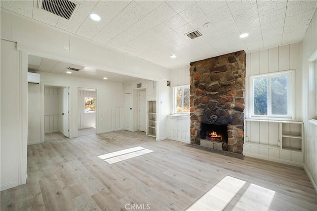 unfurnished living room featuring a stone fireplace and light wood-type flooring